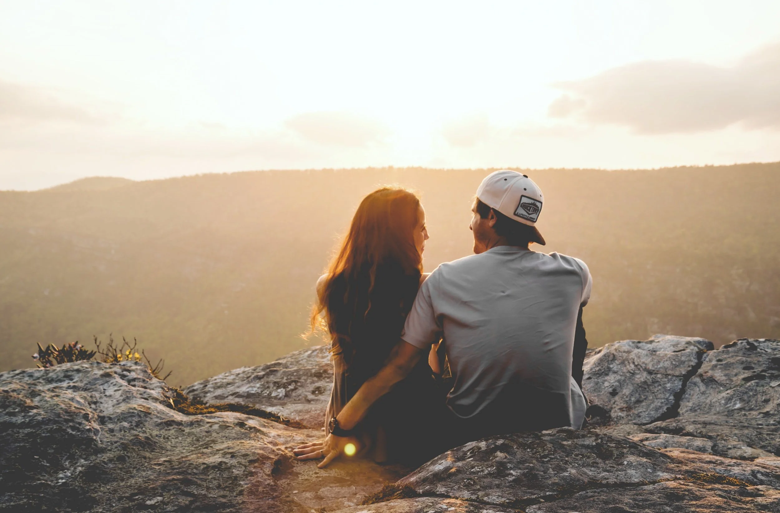 Couple embracing on a mountaintop at sunset