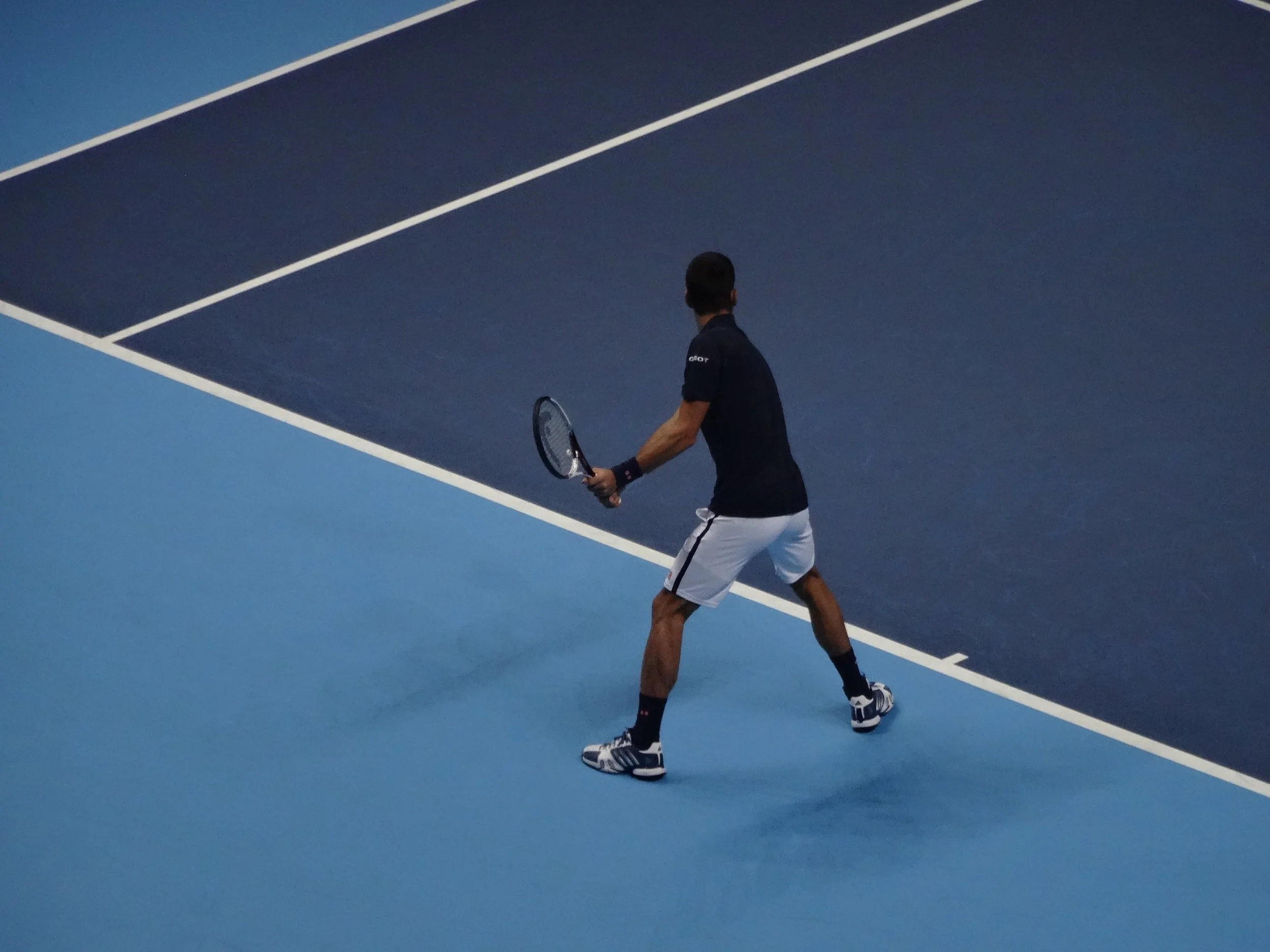 Tennis player prepares to serve on a blue court