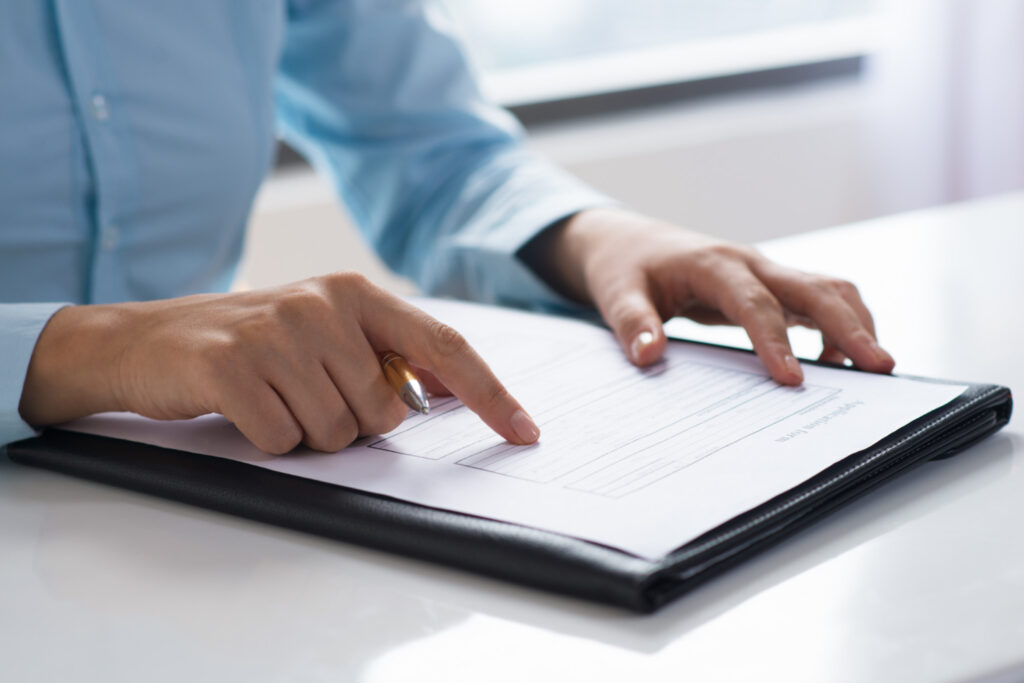 Close-up of hands filling out an application form for Australian citizenship by conferral.