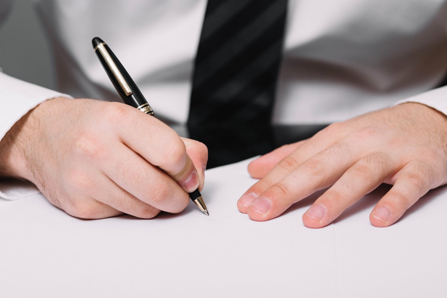 Close-up of hands signing a document with a pen. Notary public services in Adelaide.