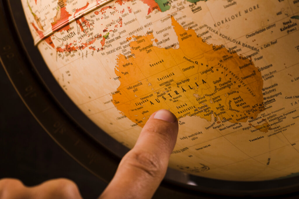 Finger pointing to Australia on a globe, preparing for the Australian citizenship test.