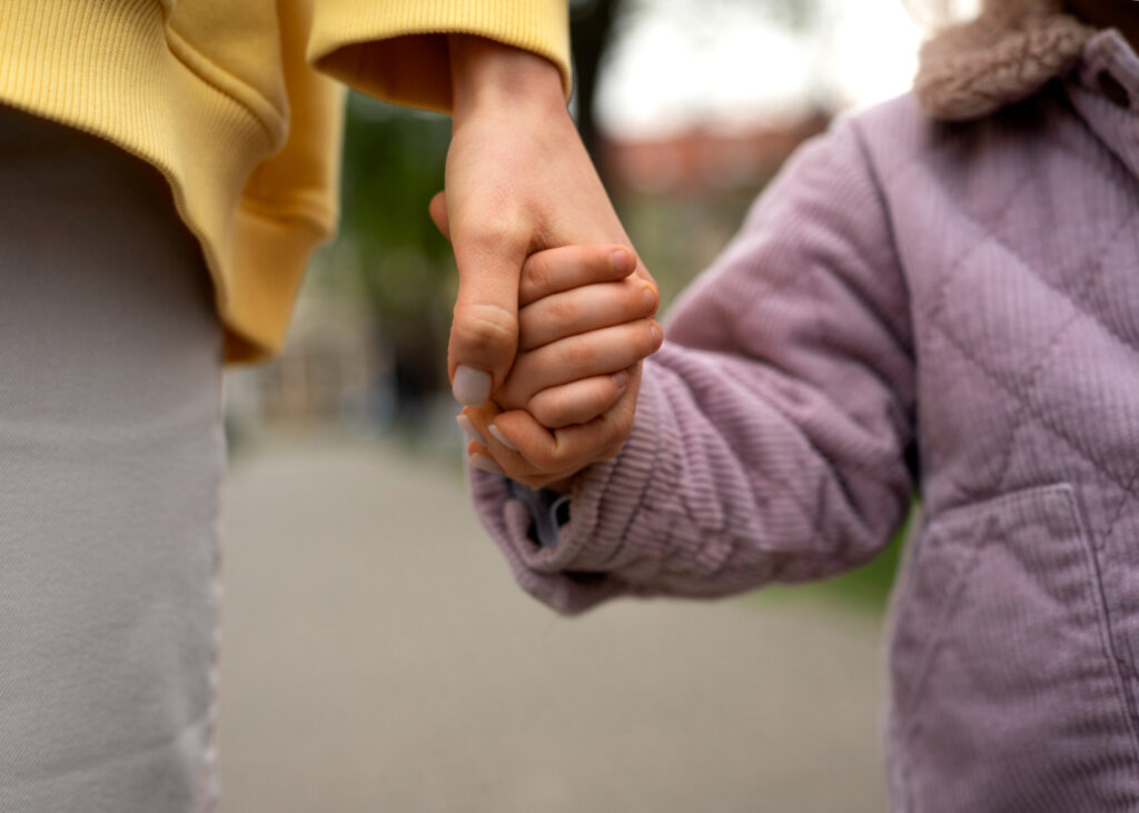 Close-up of an adult and child holding hands.