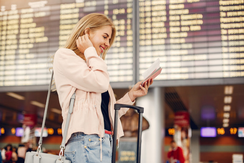Young woman at airport reviewing travel documents.