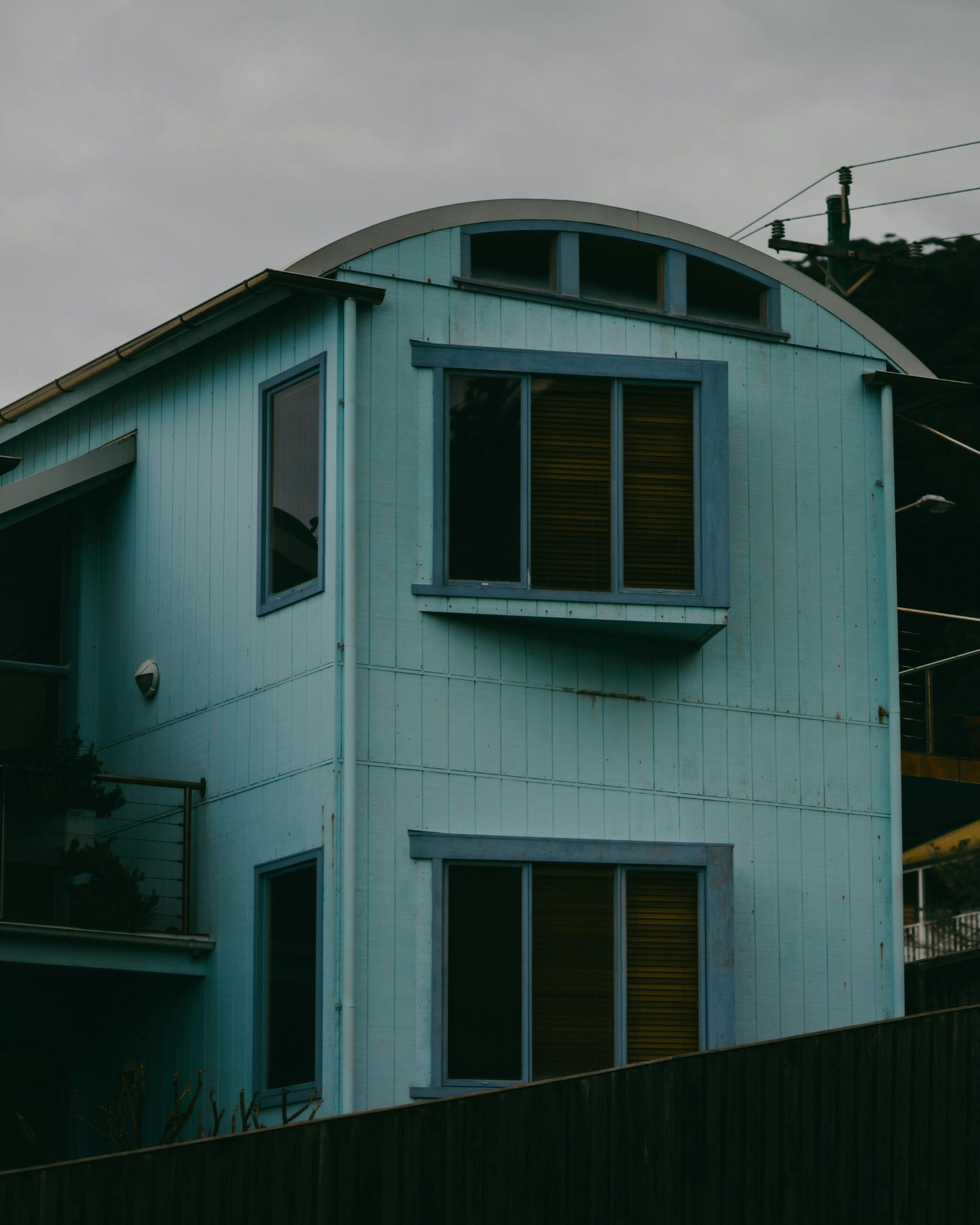 Teal house with arched roofline and multiple windows. Adelaide architecture.