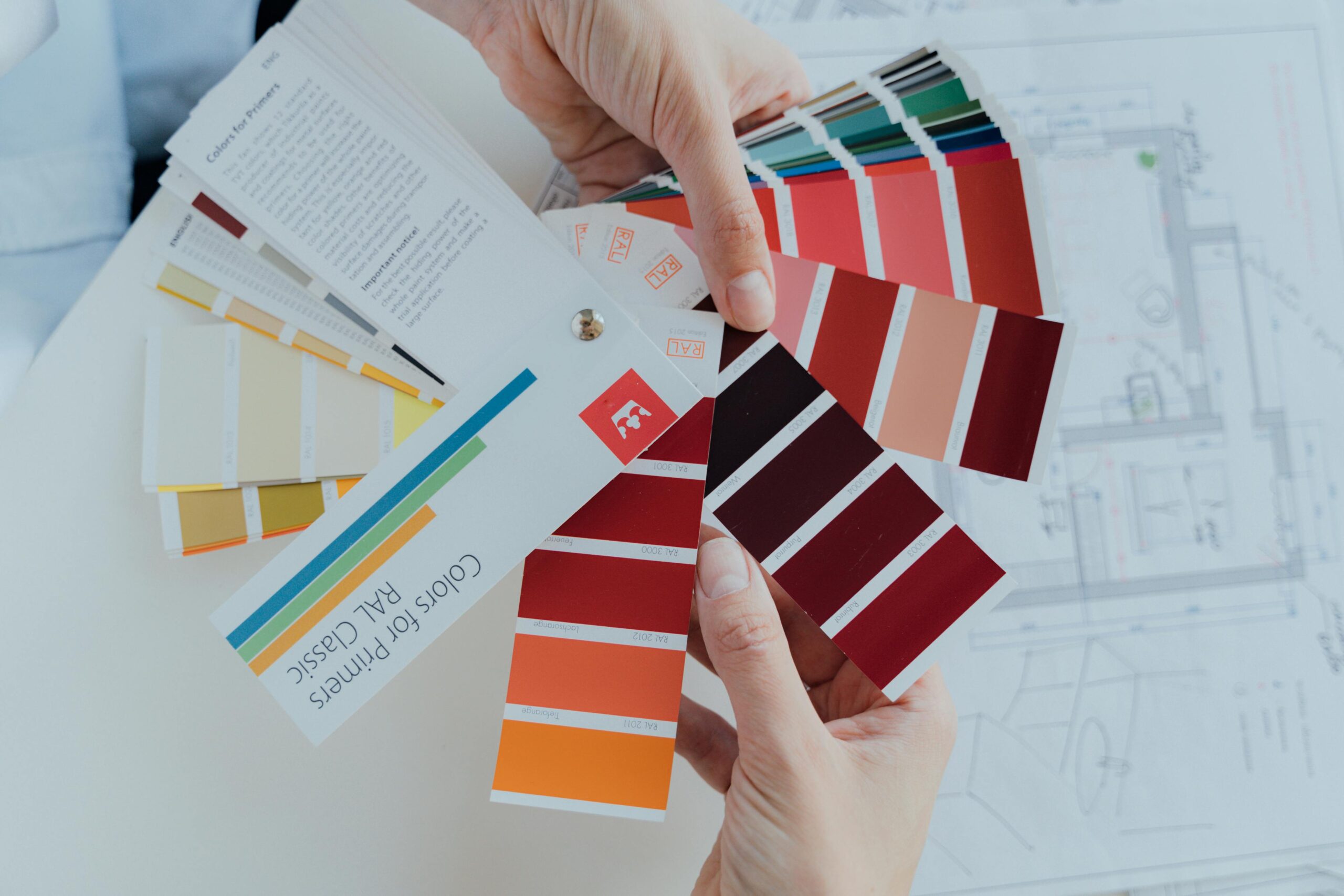 Hands holding RAL color swatches for paint primers.