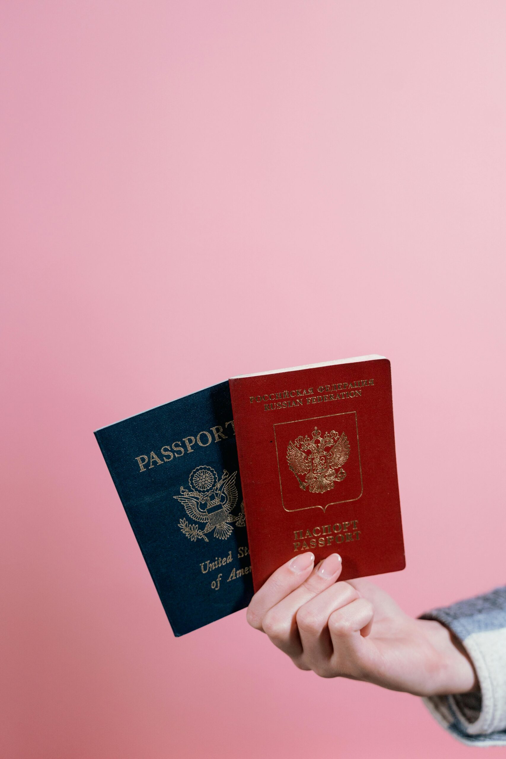 Close-up of hands holding a US and Russian passport.