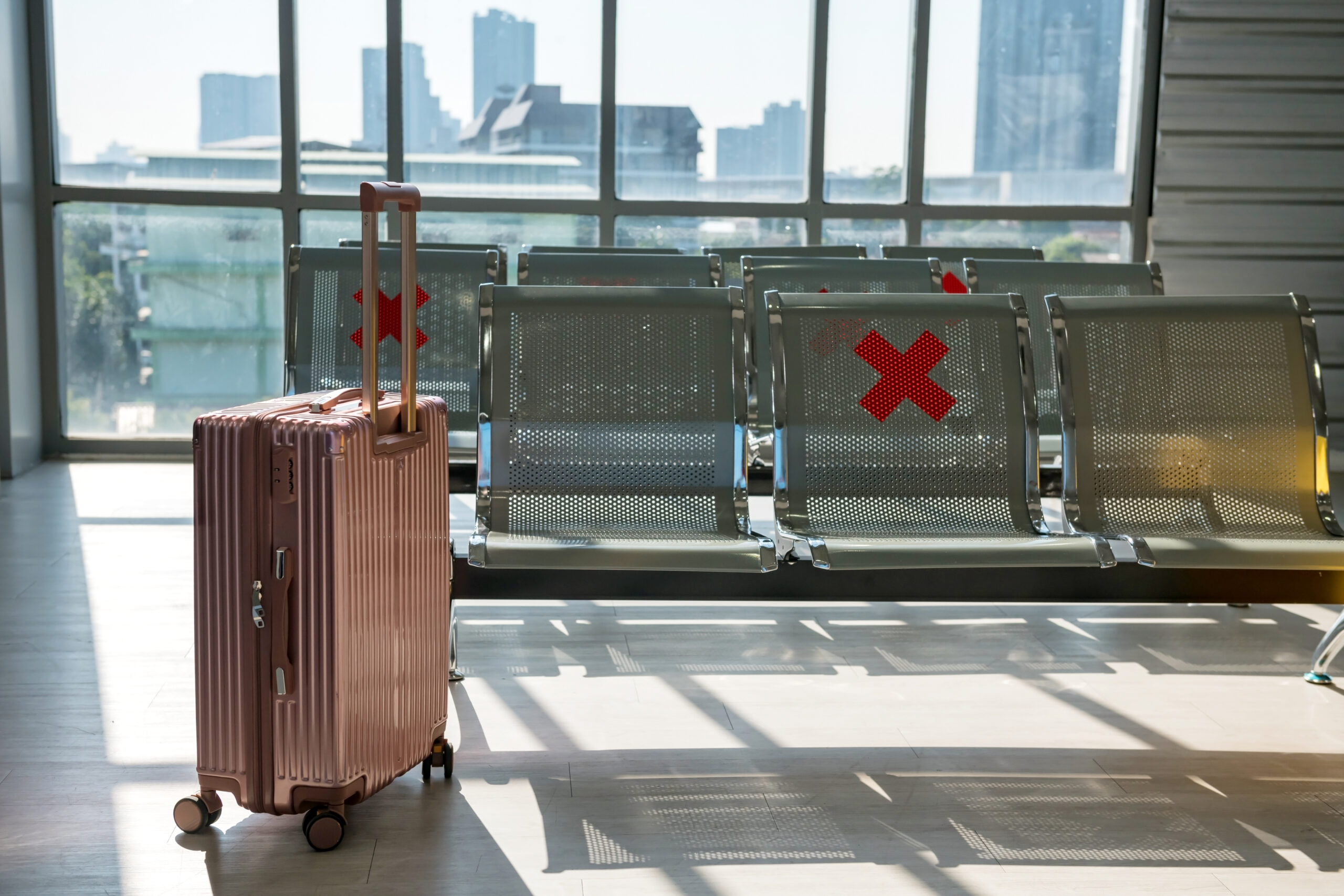 Empty airport seats marked with red Xs, a suitcase sits nearby. Australian visa refusal?