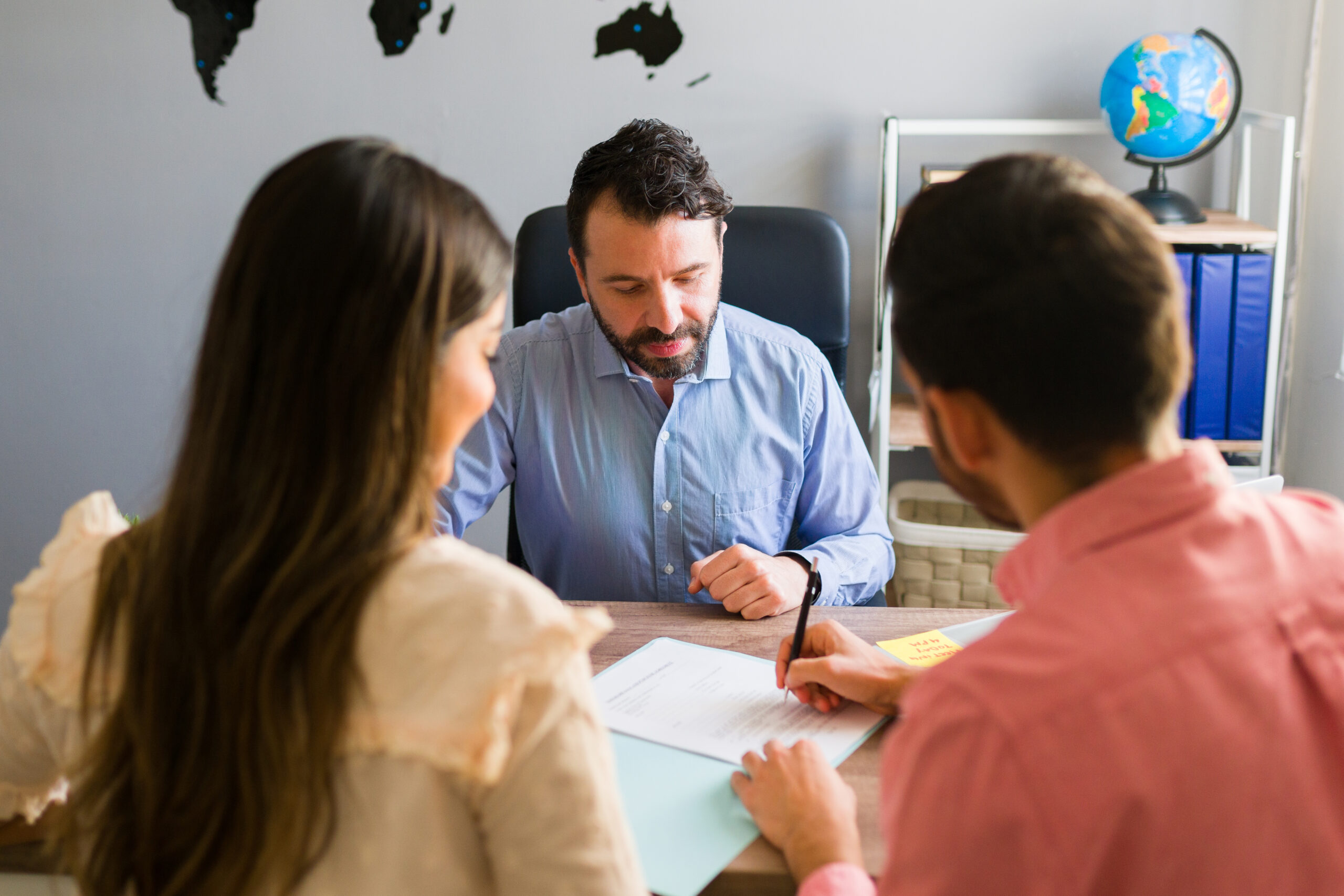 Migration lawyer consulting with couple, reviewing documents.