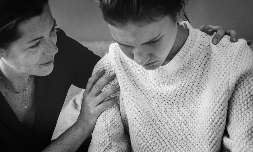 Supportive woman comforting a distressed woman. Seeking help with partner visa applications? Contact Australian immigration lawyers specializing in domestic violence cases.