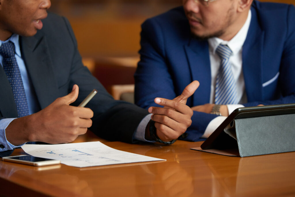 Two businessmen reviewing documents, discussing immigration law and ministerial intervention.