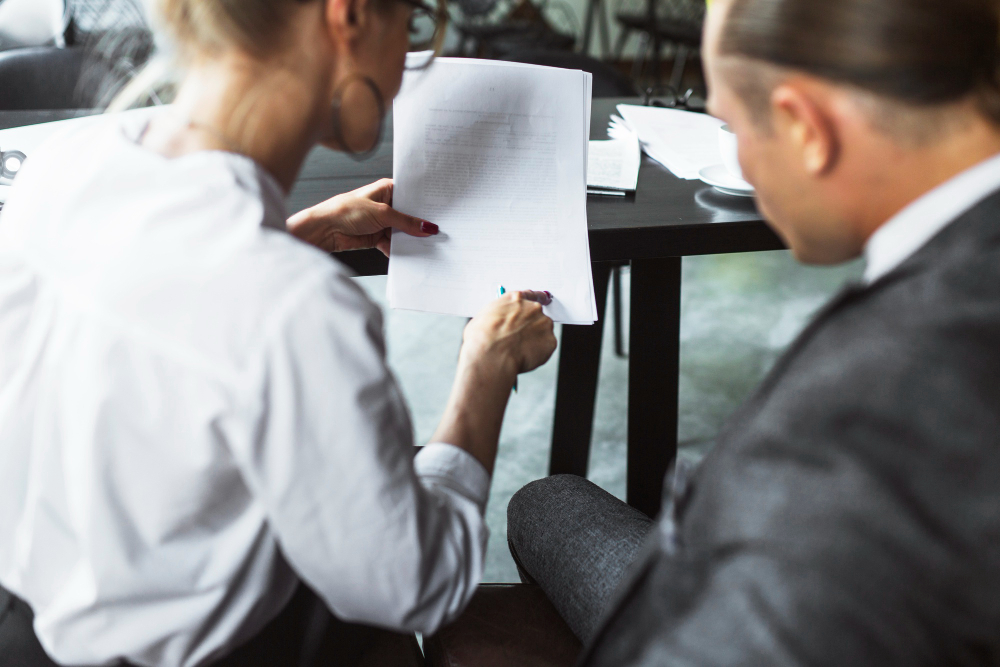 Two business professionals review legal documents, seeking ministerial intervention for immigration.