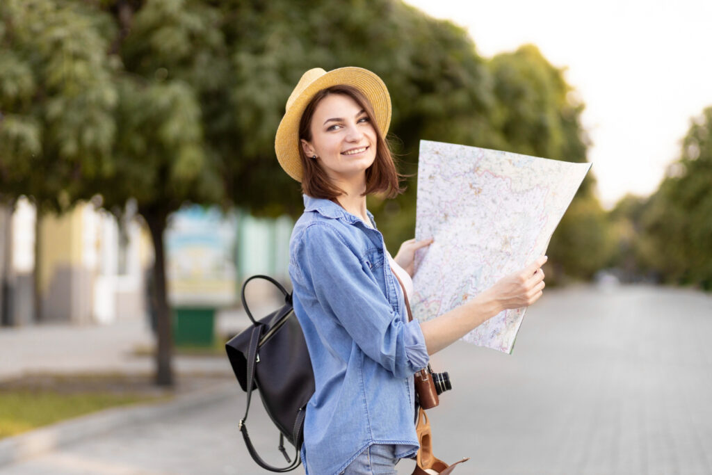 Happy tourist woman with backpack using a map.