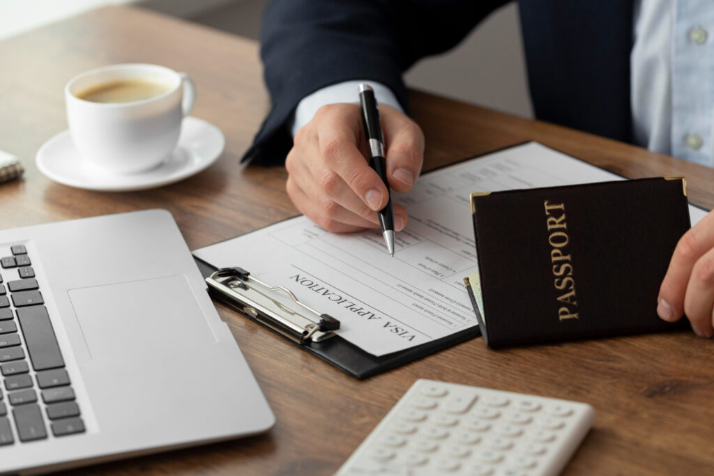 Person filling out a visa application form, with passport nearby.