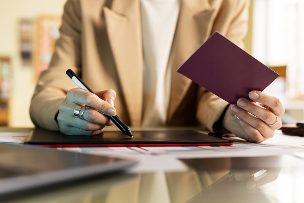 Woman reviewing immigration documents and using a stylus on a graphics tablet.