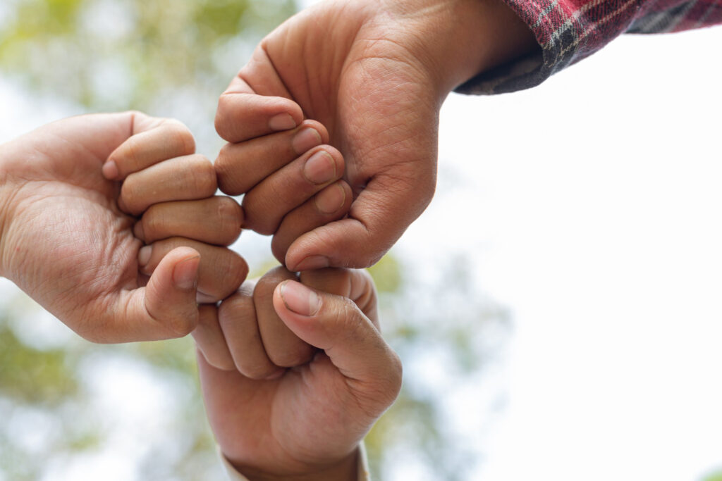 Three hands clasped together, symbolizing unity and support.
