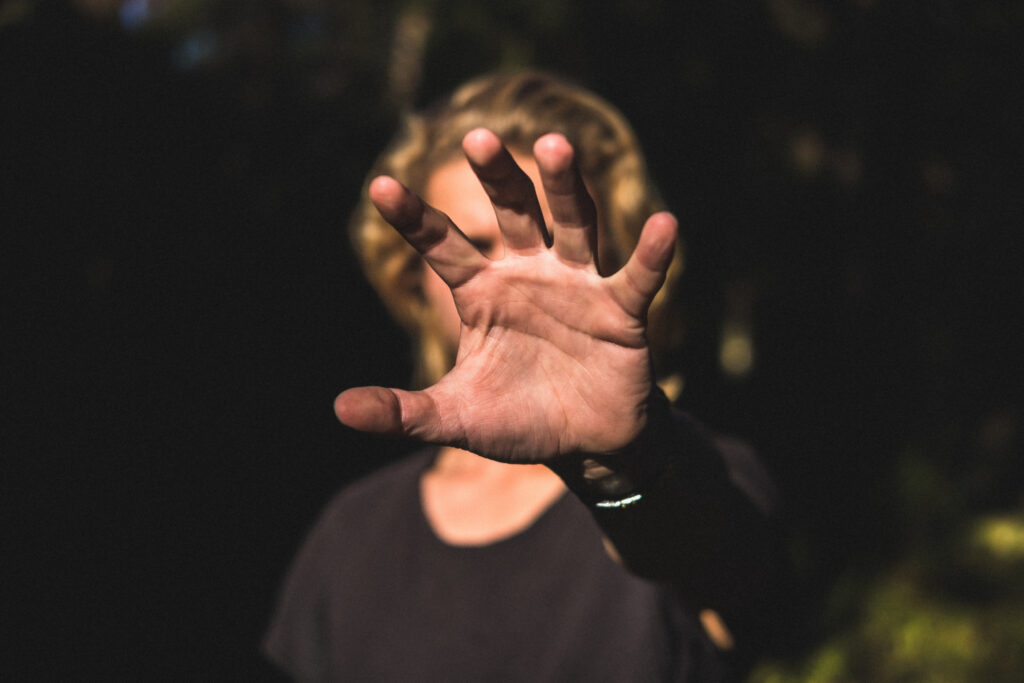 Person holding up hand, palm out, as if stopping someone.