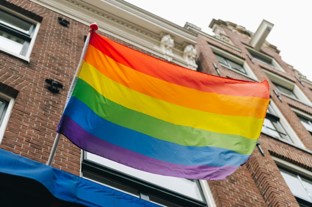 Rainbow Pride flag flies in front of a brick building. LGBTIQ+ rights.