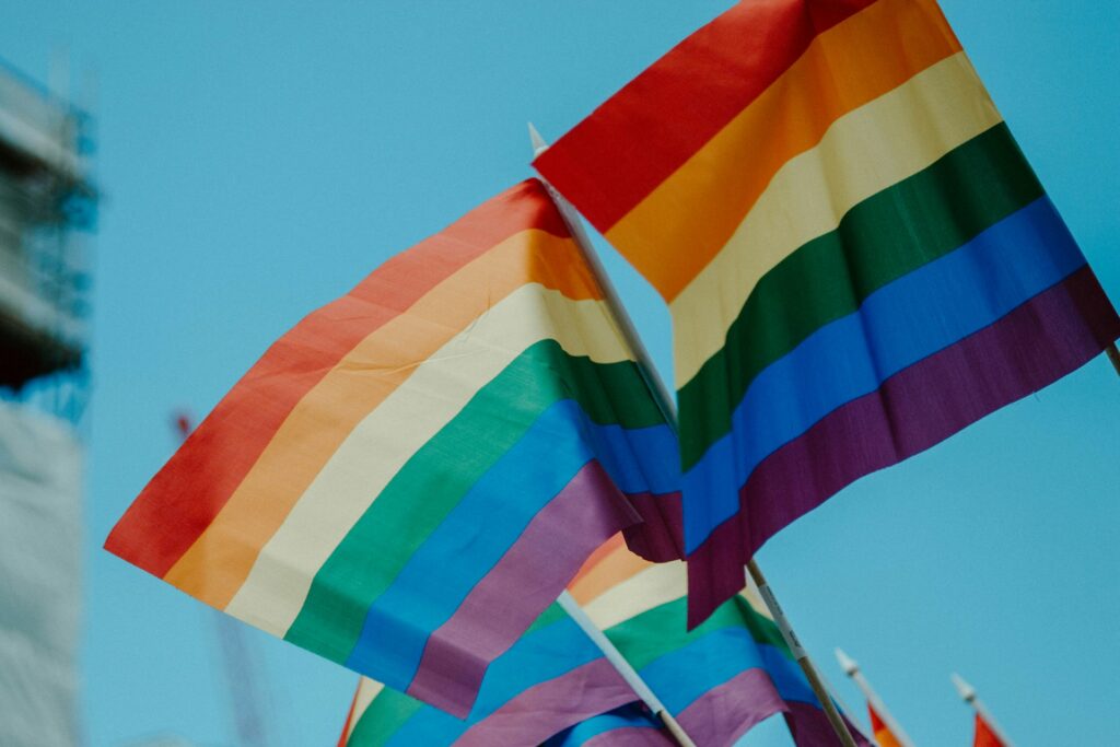 Rainbow pride flags waving against a blue sky. LGBTIQ+ rights.