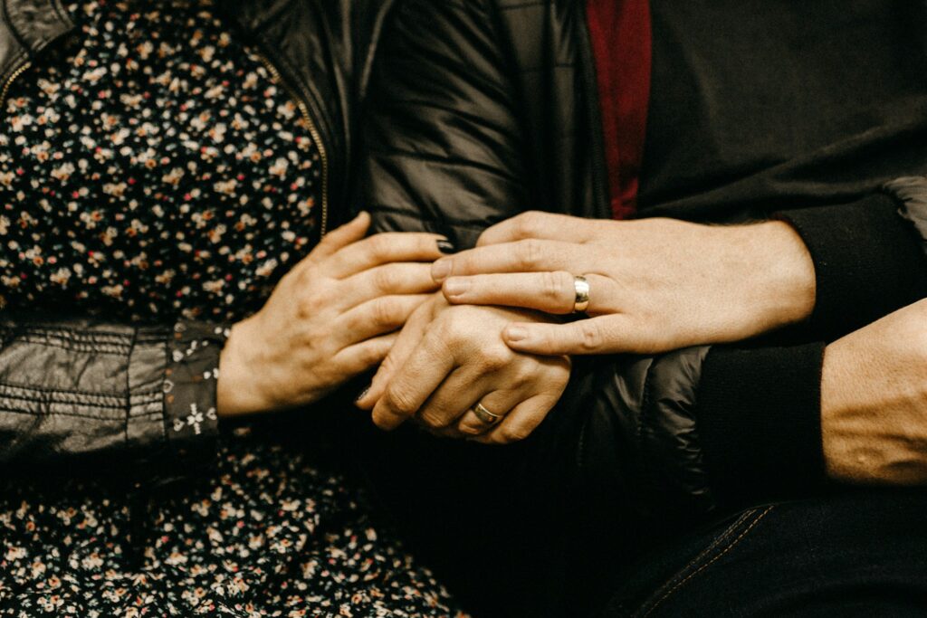 Couple holding hands, showing wedding rings. Applying for a partner visa? We can help.