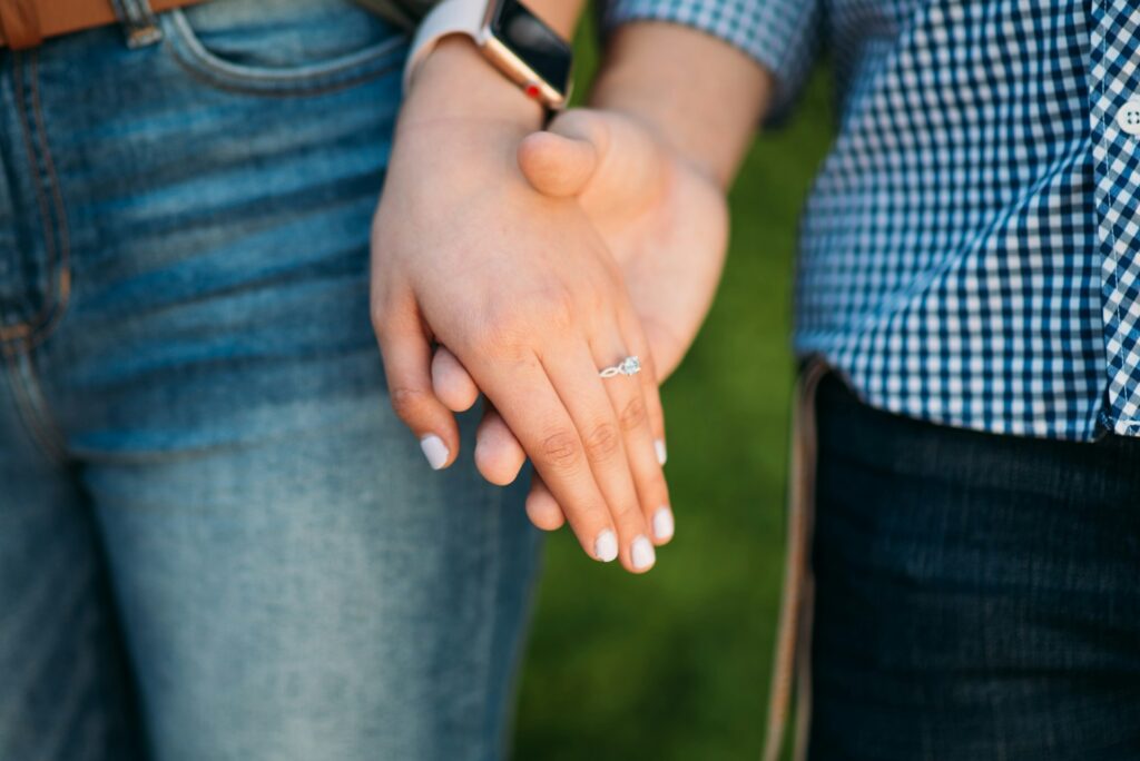 Couple holding hands, showcasing a diamond engagement ring. Prospective marriage visa.