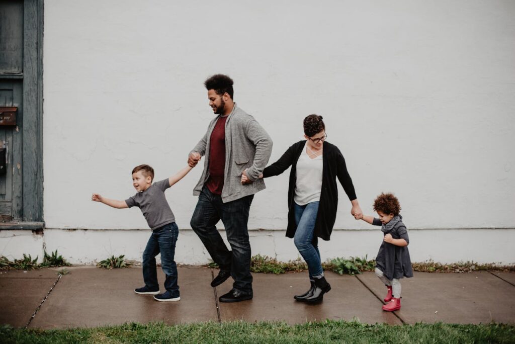 Happy family of four walking hand-in-hand. Parents and two children enjoying a stroll.