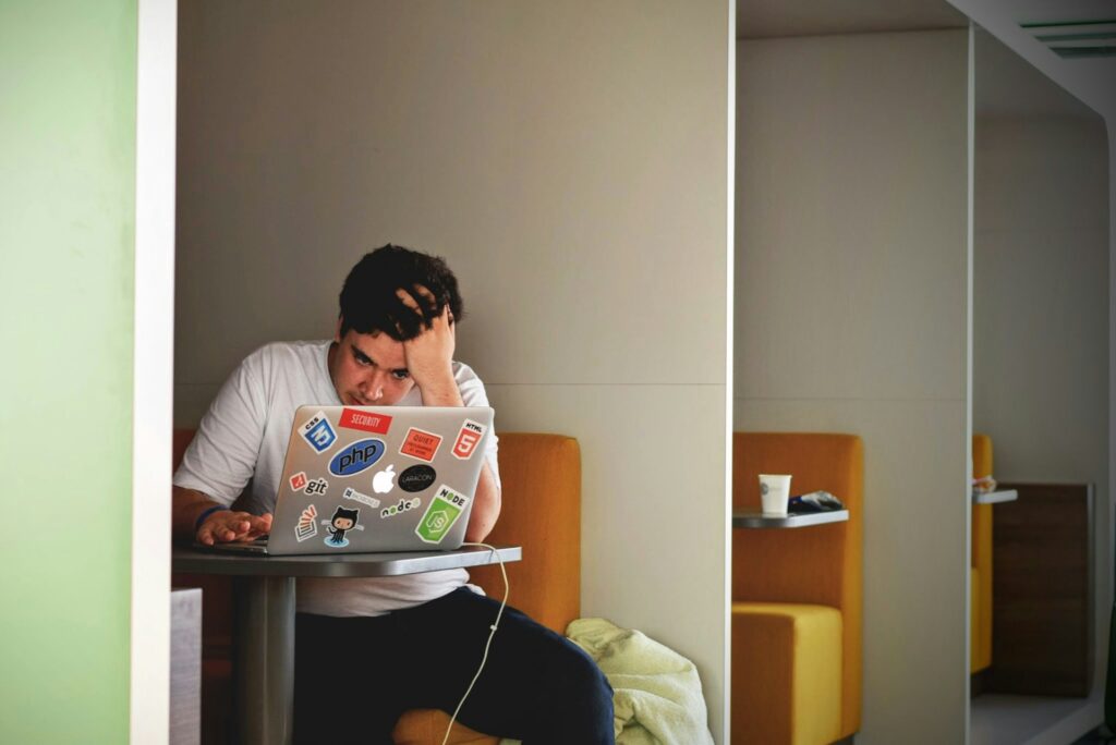 Frustrated man working on laptop, seeking help with student visa cancellation.