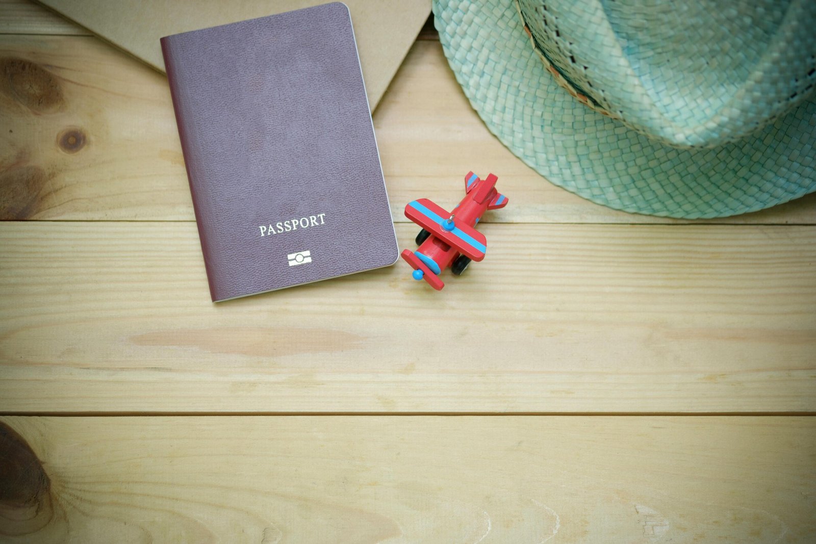 Passport, hat, and toy airplane on wood; travel plans