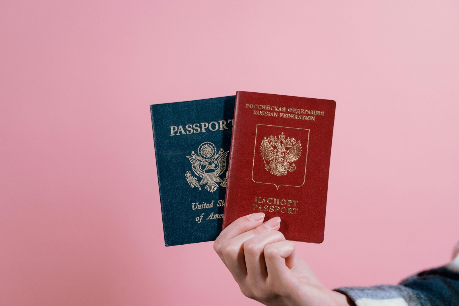 Close-up of a hand holding a US and Russian passport.