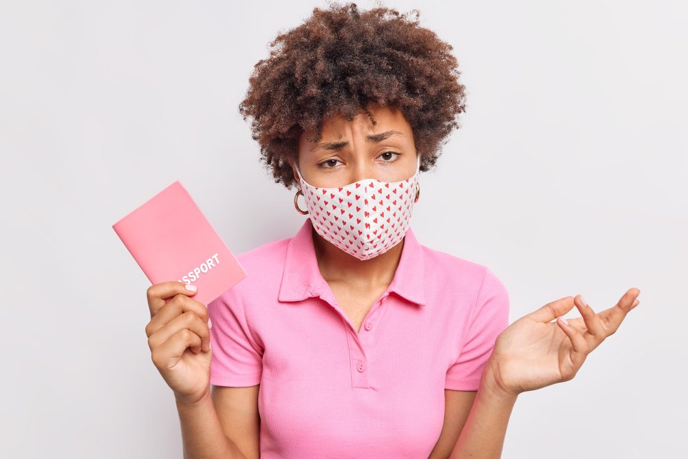 Worried woman in mask holds passport. Visa decision uncertainty after ART appeal success.